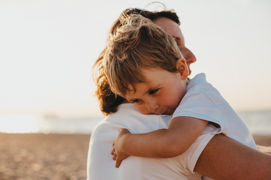 Photo by Xavier Mouton Photographie boy hugging woman during daytime